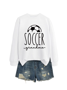 Flat lay of a white Soccer Grandma sweatshirt with distressed blue denim shorts set