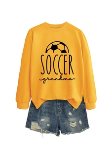 Close-up of Soccer Grandma graphic print on yellow sweatshirt with distressed denim shorts