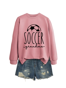Close-up of pink Soccer Grandma sweatshirt with ribbed cuffs and distressed denim shorts