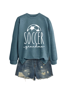 Flat lay of a misty blue Soccer Grandma sweatshirt paired with distressed denim shorts