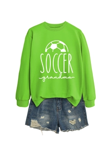 Flat lay of neon green soccer grandma sweatshirt with distressed blue denim shorts