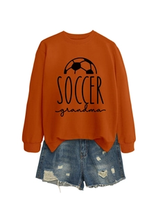 Close-up of burnt orange Soccer Grandma sweatshirt with graphic print and denim shorts