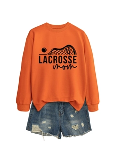 Detail of orange Lacrosse Mom sweatshirt paired with distressed denim shorts
