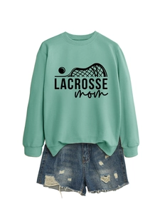 Flat lay of a mint green Lacrosse Mom sweatshirt and distressed blue denim shorts