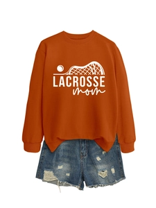 Flat lay of an orange crewneck Lacrosse Mom sweatshirt paired with distressed denim shorts