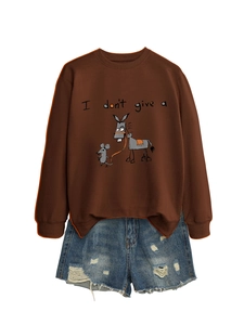 Détail d'un sweat marron avec motif animal et d'un short en jean délavé aux finitions usées