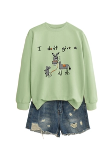 Mise à plat d'un sweat vert clair avec imprimé humoristique et mini short en jean
