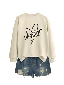 Flat lay of cream crewneck sweatshirt with Wrestling Mom print and ripped denim shorts