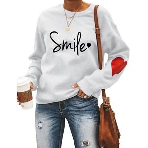Close-up of white crewneck sweatshirt with Smile lettering and red heart on the sleeve