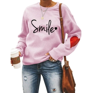 Detail of light pink sweatshirt with Smile print and red heart on the sleeve