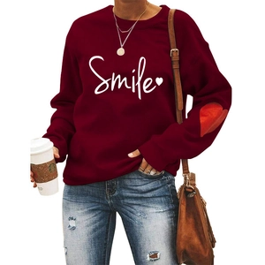 Detail of burgundy sweatshirt with Smile print and red heart patch on the sleeve
