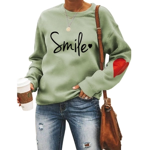 Detail of red heart patch on sleeve of green crewneck sweatshirt with Smile print