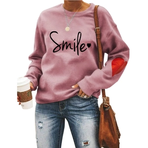 Detail of dusty pink sweatshirt featuring Smile print and red heart design on the sleeve