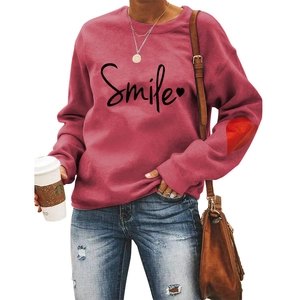 Close-up of pink Smile sweatshirt with red heart patch detail on the sleeve elbow