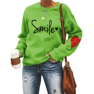 Detail of green Smile sweatshirt featuring black script and red heart on sleeve