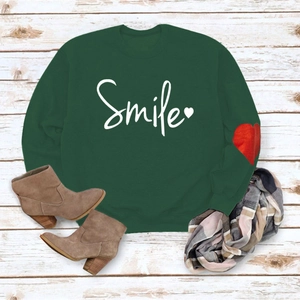 Flat lay of dark green long sleeve sweatshirt with white Smile print and heart detail