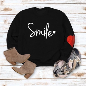 Detail showing white Smile print and red heart patch on black sweatshirt sleeve