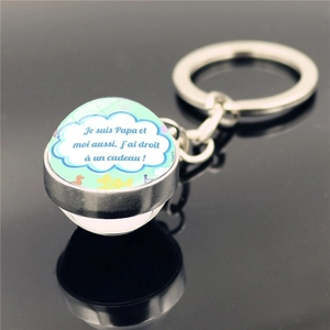 Close-up of metal keychain featuring a French themed glass dome pendant on black background
