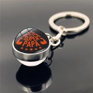 Silver metal keychain with Super Papa crystal ball pendant on a reflective surface