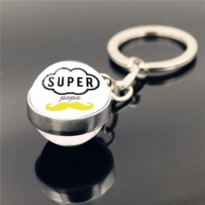Macro shot of silver keychain with Super Papa text and mustache pattern on black surface