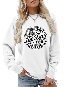 Close-up of HAVE THE DAY YOU DESERVE text and skeleton hand graphic print on white sweatshirt