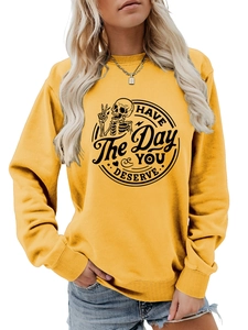 Detail of yellow sweatshirt featuring a skull graphic and HAVE THE DAY YOU DESERVE text