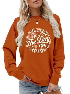 Close-up of orange crewneck sweatshirt with Have the day you deserve skull print
