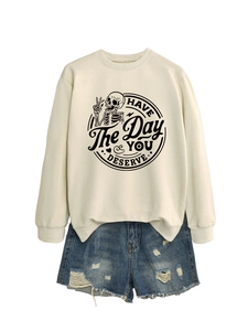 Flat lay of beige sweatshirt with skull graphic and distressed blue denim shorts set