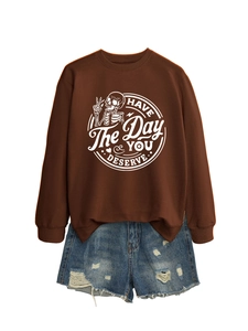 Flat lay of brown long sleeve sweatshirt with skeleton graphic and ripped denim shorts