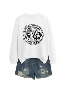 Detail of white sweatshirt with Have The Day You Deserve skeleton graphic and denim shorts