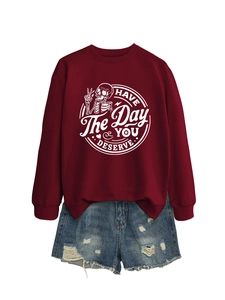 Flat lay of maroon pullover sweatshirt with white graphic print and ripped denim shorts