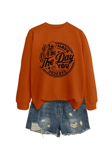 Close-up of orange long-sleeve sweatshirt with HAVE THE DAY YOU DESERVE graphic and skull