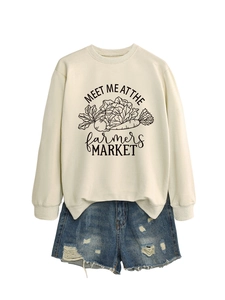 Détail du sweat crème avec imprimé marché et short en jean bleu avec déchirures
