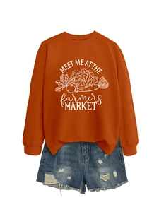 Mise à plat d'un sweat orange imprimé et d'un short en jean aux bords effilochés