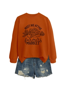 Détail du sweat orange avec imprimé Farmers Market et short en jean déchiré