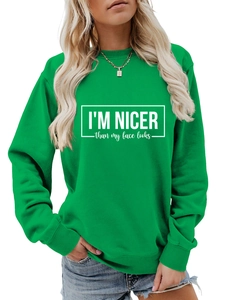 Close-up of white text print I'm Nicer than My Face Looks on green crewneck sweatshirt