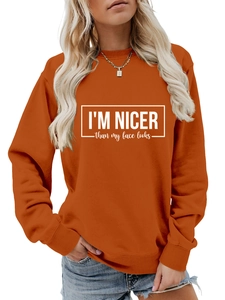 Detail of orange crewneck sweatshirt featuring white I'm nicer than my face looks slogan