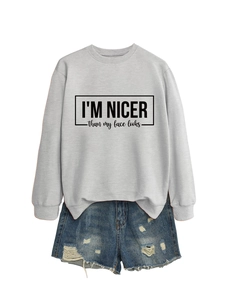 Flat lay of light grey sweatshirt with I'm nicer than my face looks slogan and denim shorts