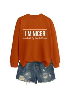 Detail of orange sweatshirt with I'm nicer than my face looks print and denim shorts
