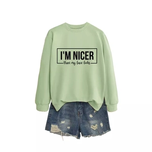 Mint green pullover sweatshirt with text print and distressed denim shorts on white background