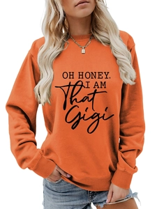 Close-up of bright orange sweatshirt with OH HONEY I AM THAT GIGI black graphic print