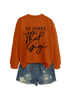 Detail of caramel crewneck sweatshirt with 'OH HONEY' text and distressed denim shorts