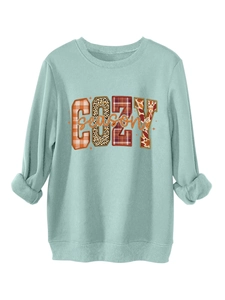 Detalle del estampado COZY season con motivos de leopardo y cuadros en sudadera menta