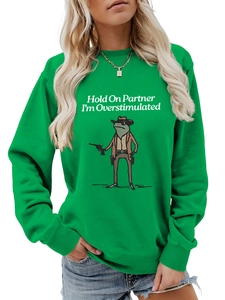 Detail of green crewneck sweatshirt featuring cowboy frog graphic and slogan text