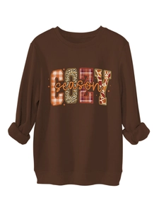 Detalle del estampado COZY season con patrones de leopardo y cuadros en sudadera marrón