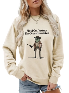 Close-up of beige sweatshirt featuring a cowboy frog with funny text and ribbed cuffs