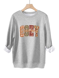 Detalle del estampado COZY season con motivos de leopardo y cuadros en sudadera gris