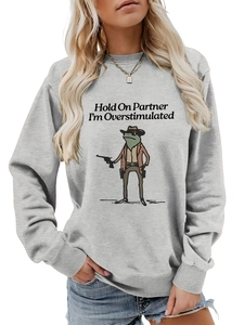 Detail of grey sweatshirt featuring a cowboy frog graphic and overstimulated slogan