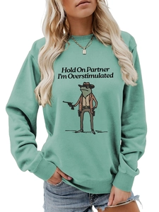 Detail of mint green sweatshirt showing cowboy frog print and ribbed crew neck finish