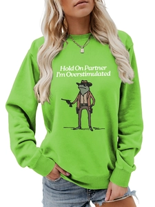 Detail of Hold On Partner I'm Overstimulated slogan and cowboy frog on green sweatshirt